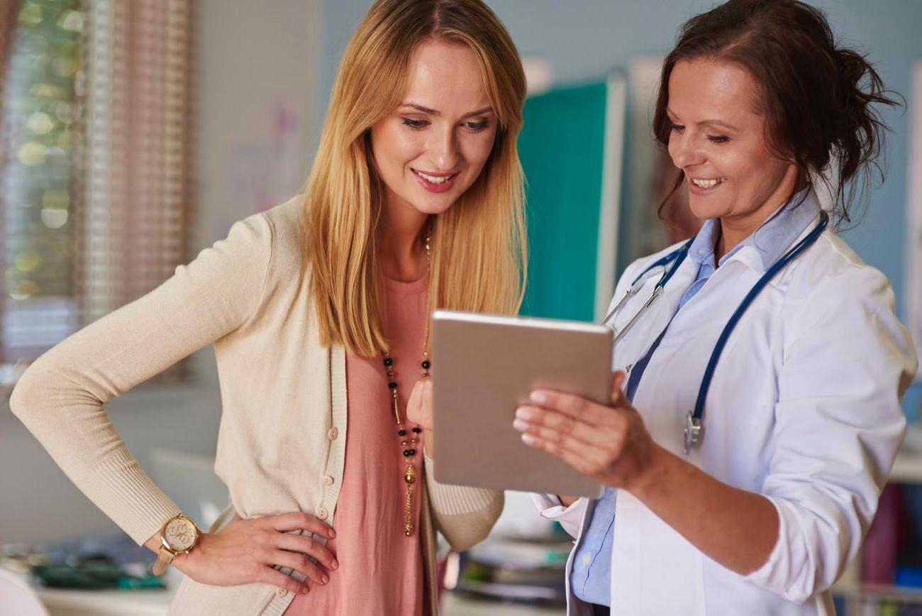 Woman showing a patient an iPad. Image by Freepik.